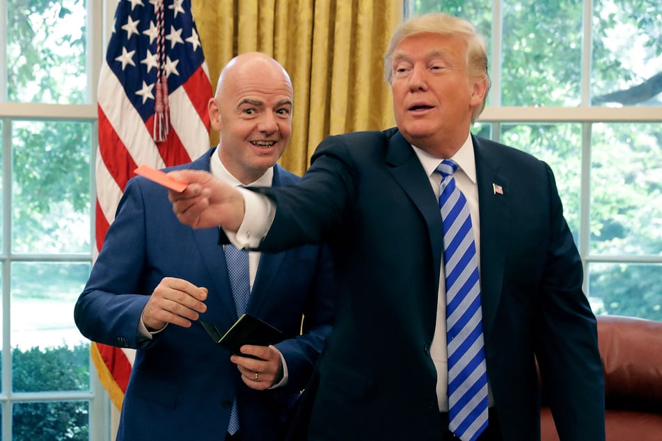 US President Donald Trump (r.) pretends to give a red card to members of the news media with FIFA President Gianni Infantino in the Oval Office at the White House on August 28, 2018.