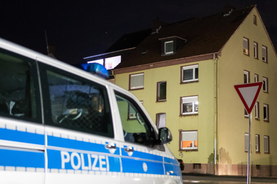 Ein Streifenwagen der Polizei steht vor dem Mehrfamilienhaus, in dem zuvor Durchsuchungen stattgefunden haben.