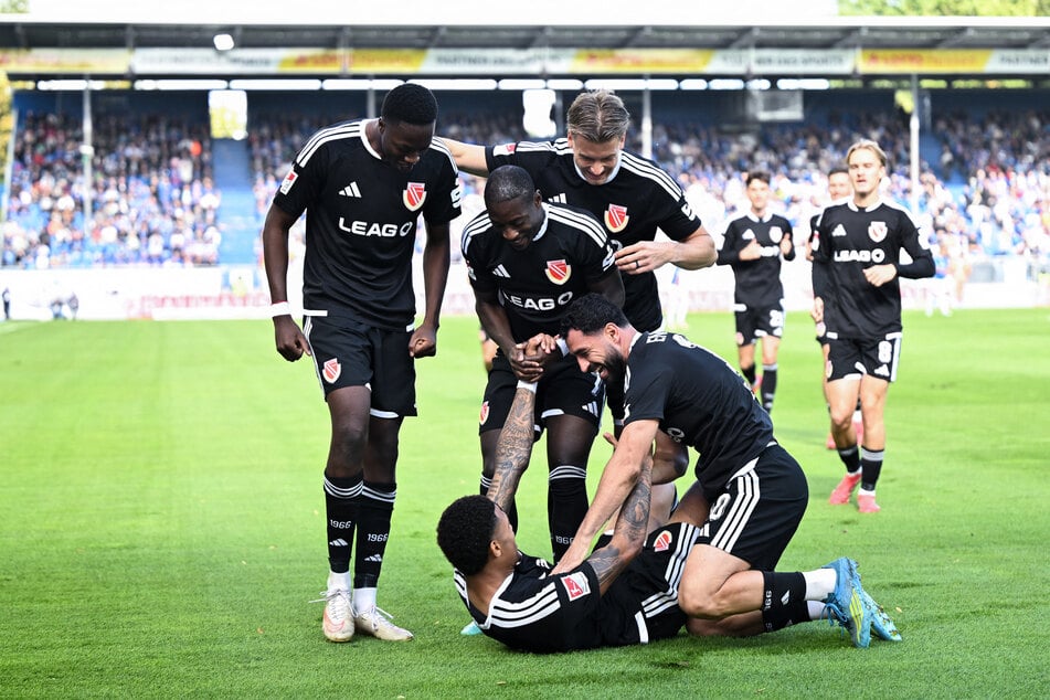 Justin Butler (am Boden) trifft, seine Mitspieler feiern ihn.