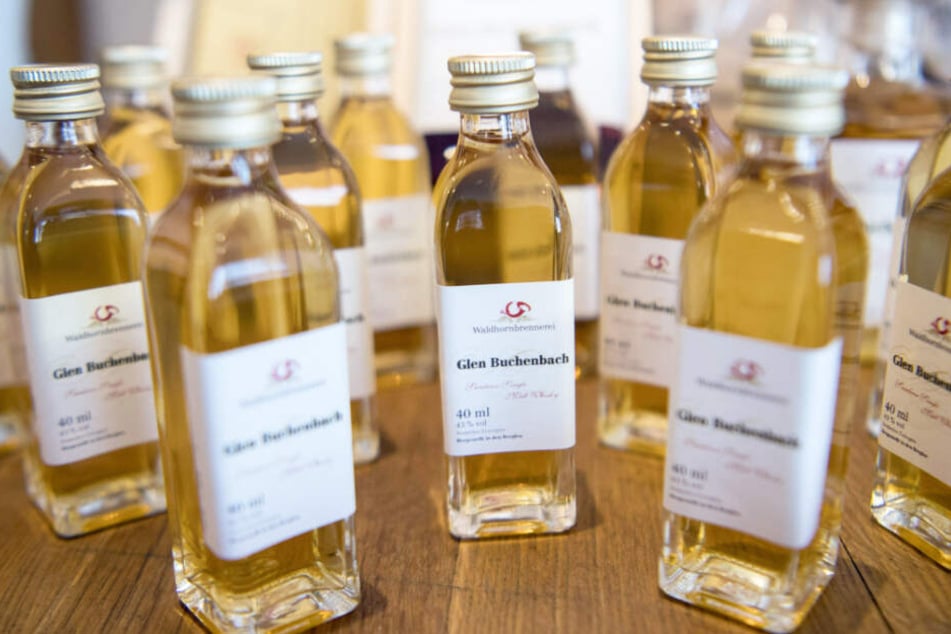 Mehrere Whisky-Flaschen mit der Aufschrift "Glen Buchenbach" stehen auf einem Tisch. Sie müssen jetzt umbenannt werden.