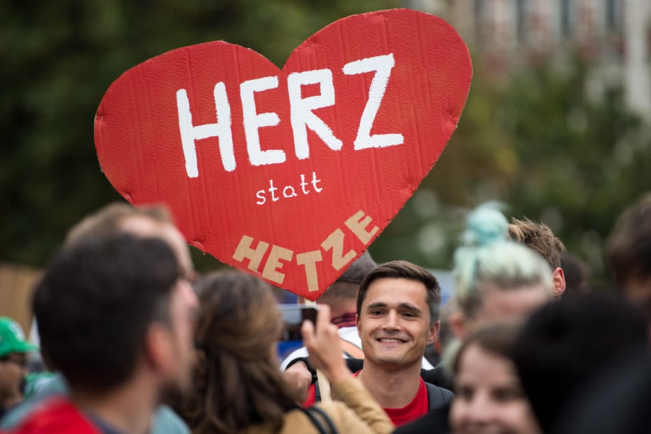 Ein Demo-Teilnehmer hält ein Schild mit dem Schriftzug "Herz statt Hetze".