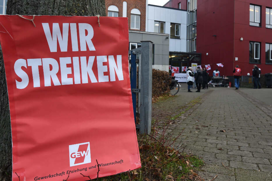 Ein Schild mit "Wir Streiken" lehnt am Eingang einer Berufsschule. (Archivbild)