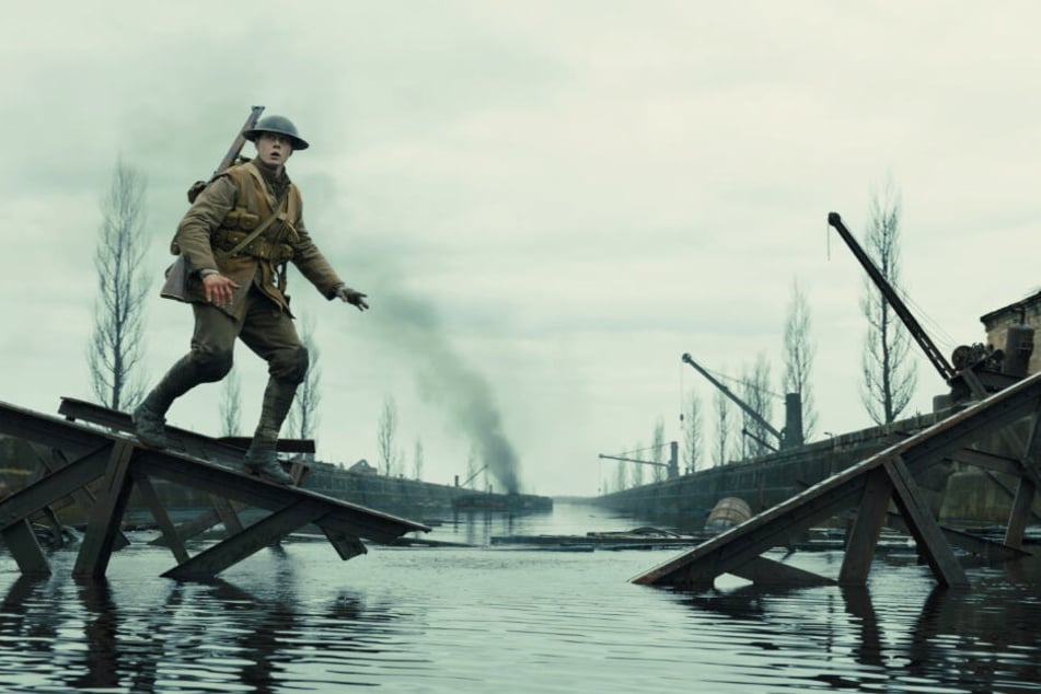 Schofield (George MacKay) balanciert auf einem Geländer einer kaputten Brücke.