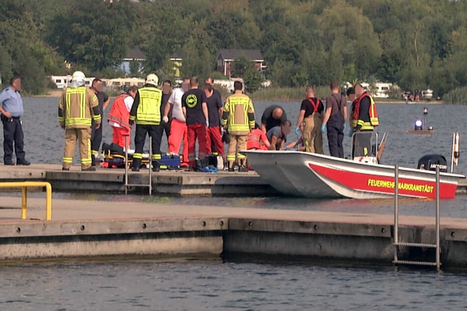 Auf der Steganlage des Segelclubs kümmern sich Rettungskräfte um die entkräfteten Männer.