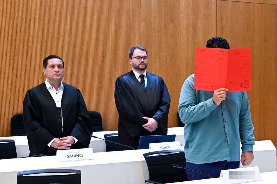 Der Angeklagte Farhad N. (25) steht mit seinen Anwälten Ömer Sahinci (l.) und Johann Bund (2.v.l.) im Prozesssaal.