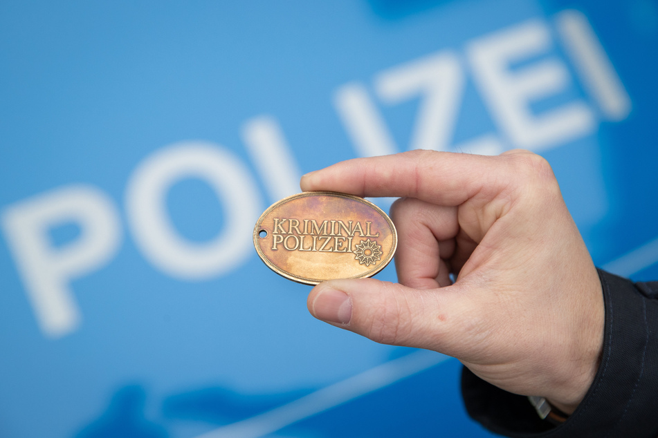 Ein Polizist hält eine Dienstmarke der Kriminalpolizei in seiner Hand. (Symbolbild)