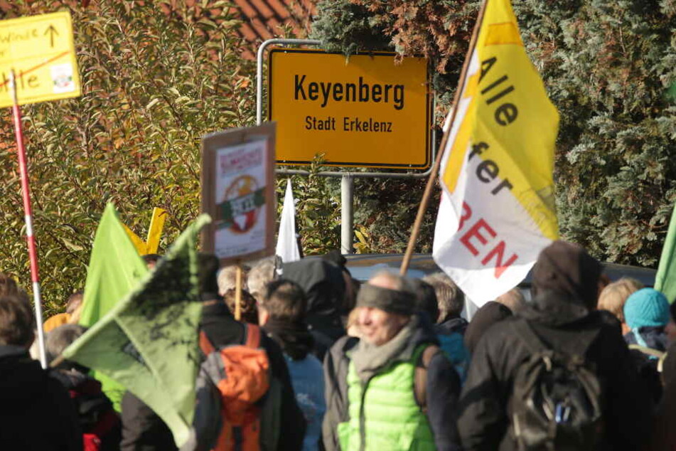 Demonstranten stehen mit Flaggen vor dem Ortseingangsschild des Dorfes Keyenberg.