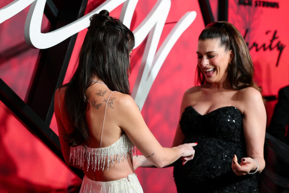 Dakota Johnson zeigt sich von Anne Hathaways Babykugel fasziniert.