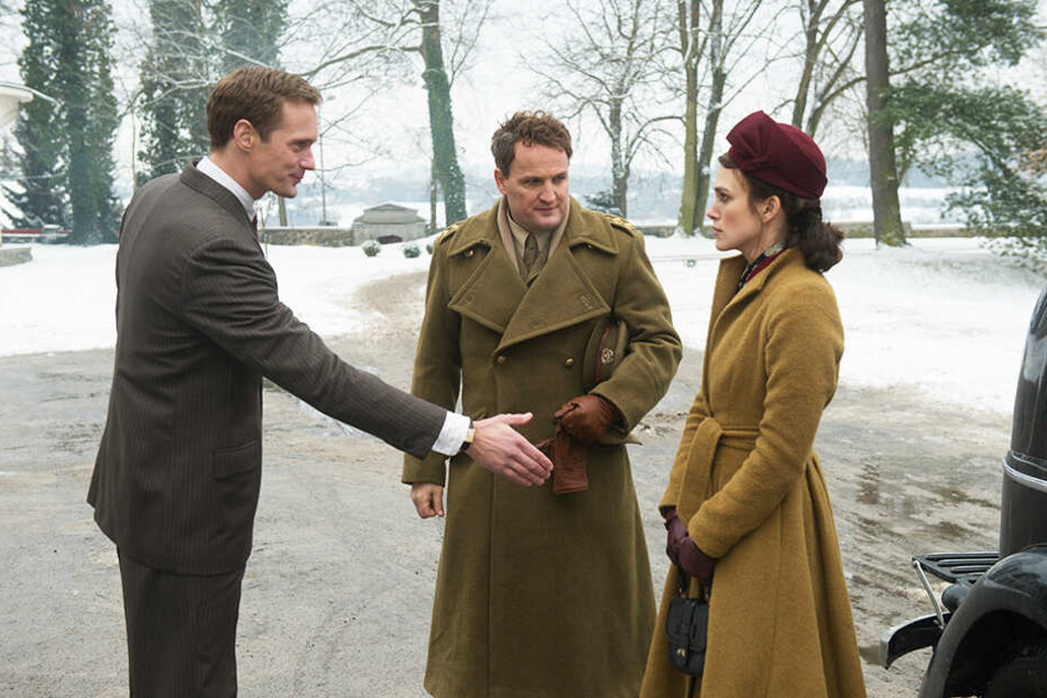 Rachael Morgan (r., Keira Knightley) und ihr Mann Lewis (M., Jason Clarke) werden von Stephan Lubert (Alexander Skarsgård) willkommen geheißen.