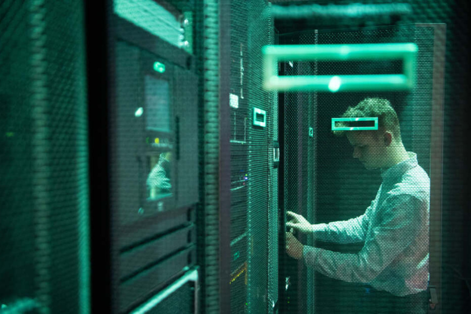 Ein Mitarbeiter des IT-Unternehmens Hewlett Packard Enterprise steht im Technologiezentrum an einem Serverschrank.