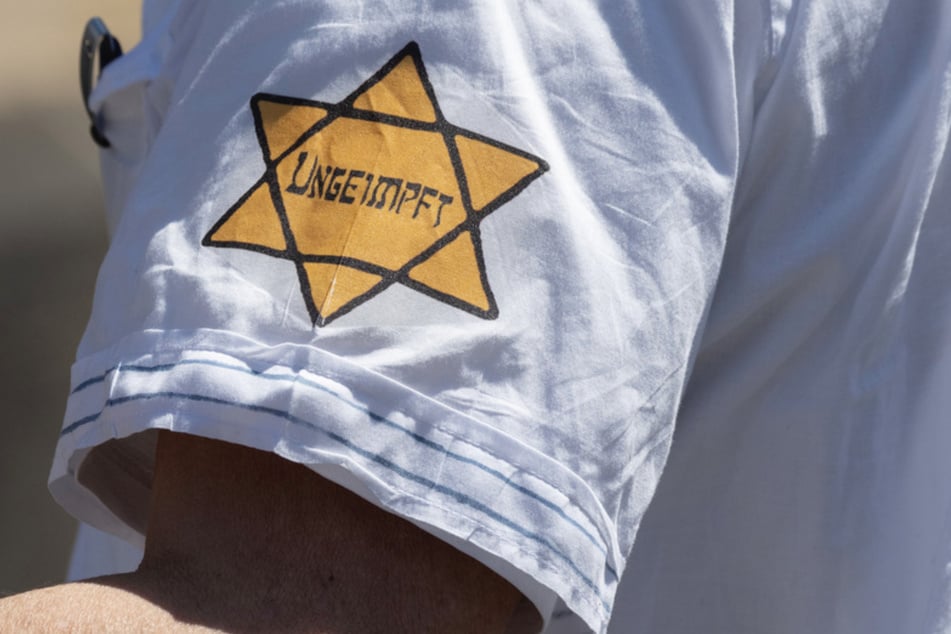 "Ungeimpft" steht auf einem nachgebildeten Judenstern am Arm eines Mannes, der versucht hatte, sich unter die Teilnehmer einer Corona-Demonstration zu mischen.