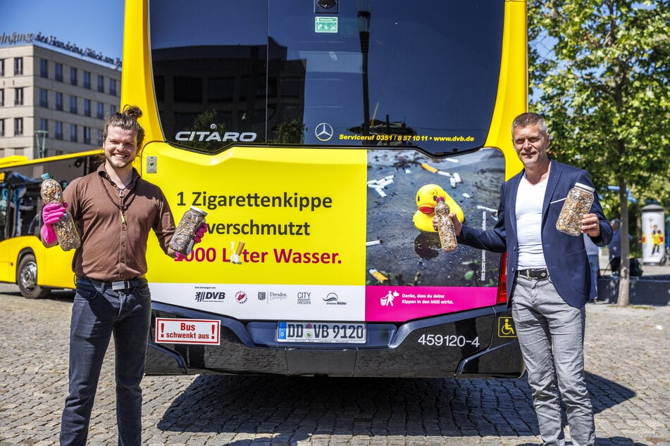 Alexander Kempe (28, "pinke Hände") und Lars Seiffert (53, DVB) vor einem der kritischen Werbeplakate auf der Rückseite der städtischen Busse.