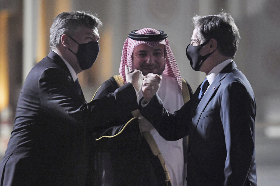 US-Außenminister Antony Blinken (59,r), wird von John Desrocher (l), Botschafter der USA in Katar, und Ibrahim Fakhroo, Direktor für Protokoll des Auswärtigen Amtes in Kabul, am Old Doha Flughafen begrüßt.