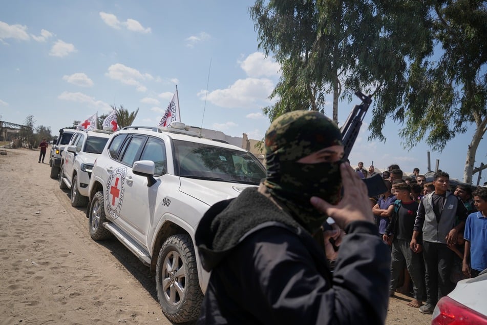 Fahrzeugen des Roten Kreuzes mit freigelassenen Geiseln bahnen sich ihren Weg durch Gruppen von Palästinensern und Hamas-Bewaffneten.