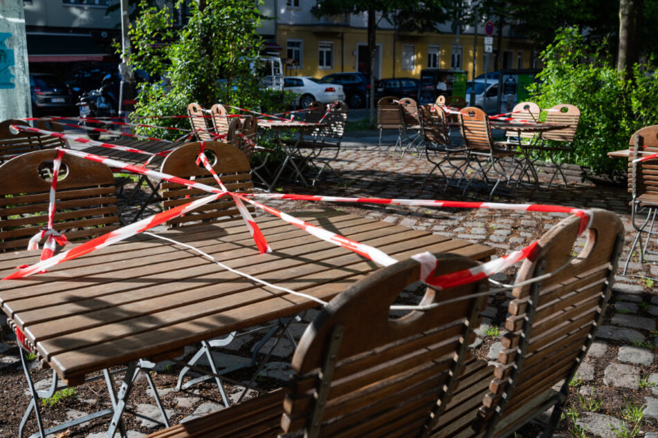 Vor einem Restaurant sind die Tische mit Flatterband verbunden.