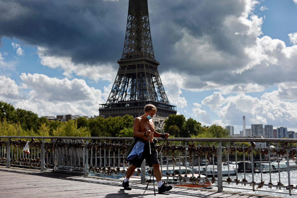 Ein Mann betreibt auf einer Brücke mit Blick auf den Eiffelturm Nordic Walking und trägt dabei einen Mundschutz. Auch Paris wurde nun als Risikogebiet eingestuft.