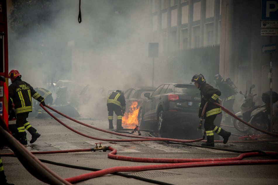 Einsatzkräfte löschen die Fahrzeug-Brände.