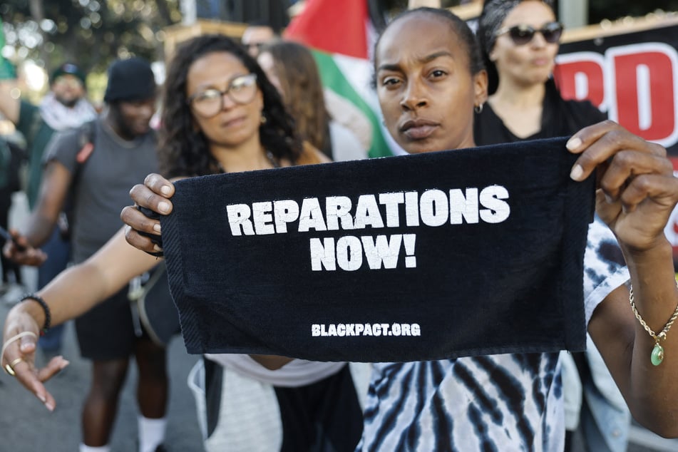 A protester holds sign reading "Reparations Now!" during a rally in honor of George Floyd on May 21, 2025, in Los Angeles, California.