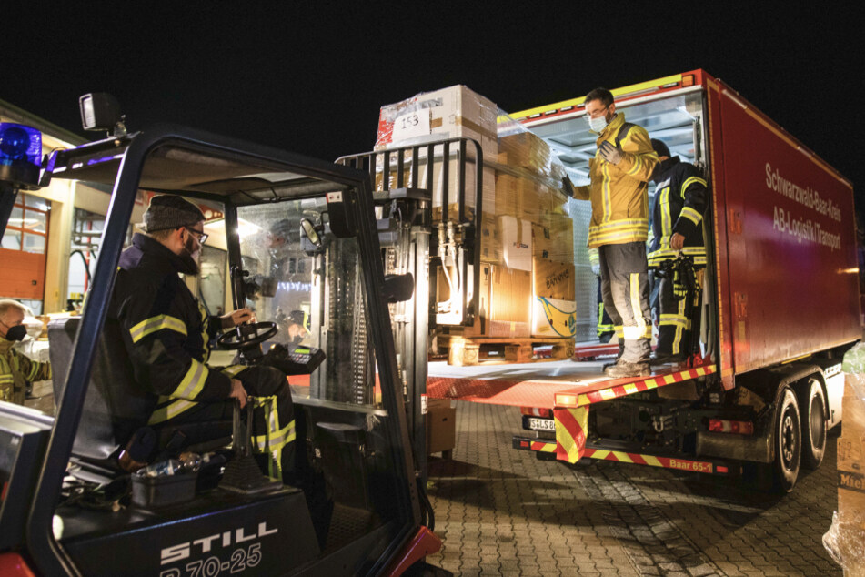 Feuerwehrleute verladen eine Palette mit Hilfsgütern auf einen Lkw.