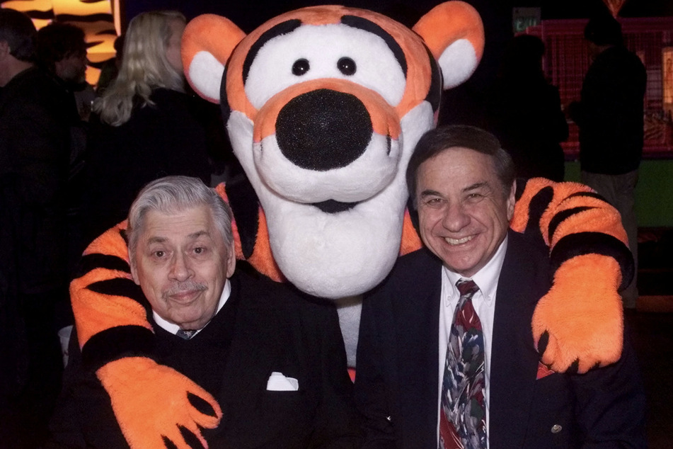 Robert Sherman (l.) and his brother Richard Sherman pose with Tigger at a party following the premiere of The Tigger Movie.
