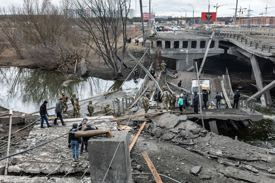 People cross a destroyed bridge as they evacuate the city of Irpin, northwest of Kyiv, during a heavy shelling and bombing.