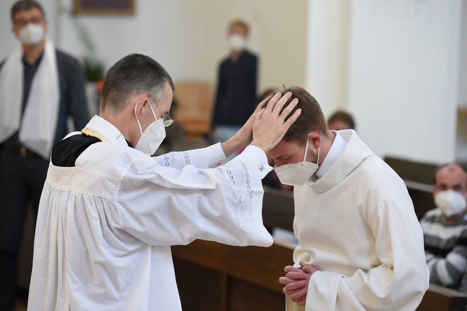 Pfarrvikar Wolfgang Rothe (53, l.) segnet Henry Frömmichen (21) bei einem Gottesdienst.