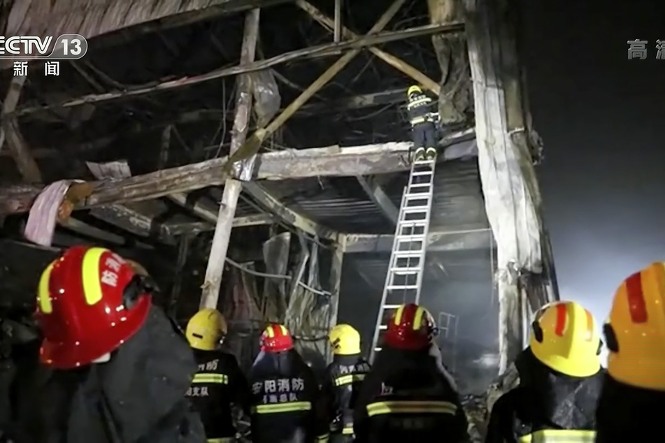 Rettungskräfte klettern mit einer Leiter in die Überreste des Brandes in einer Fabrik in der zentralchinesischen Provinz Henan.