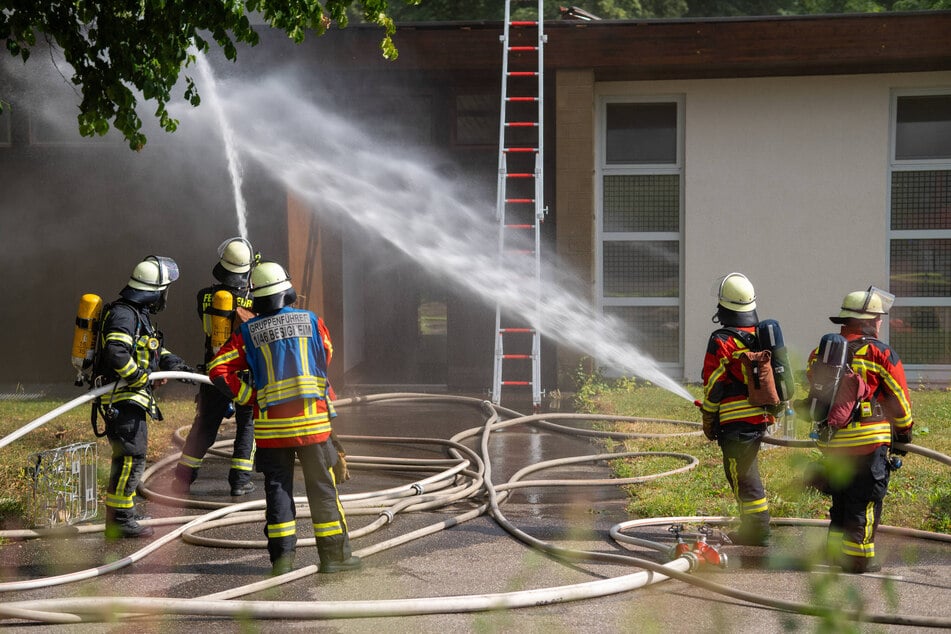 Feuerwehrmänner kämpfen gegen den Brand einer Aussegnungshalle.
