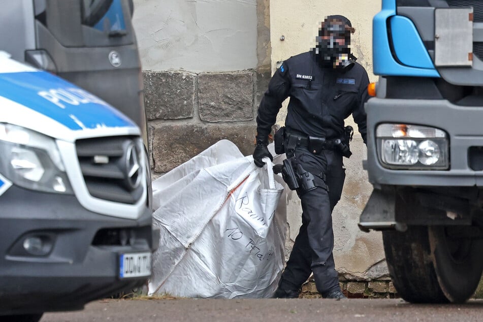 Ein Beamter schleppte einen Sack voller Cannabis-Pflanzen aus dem Gebäude.