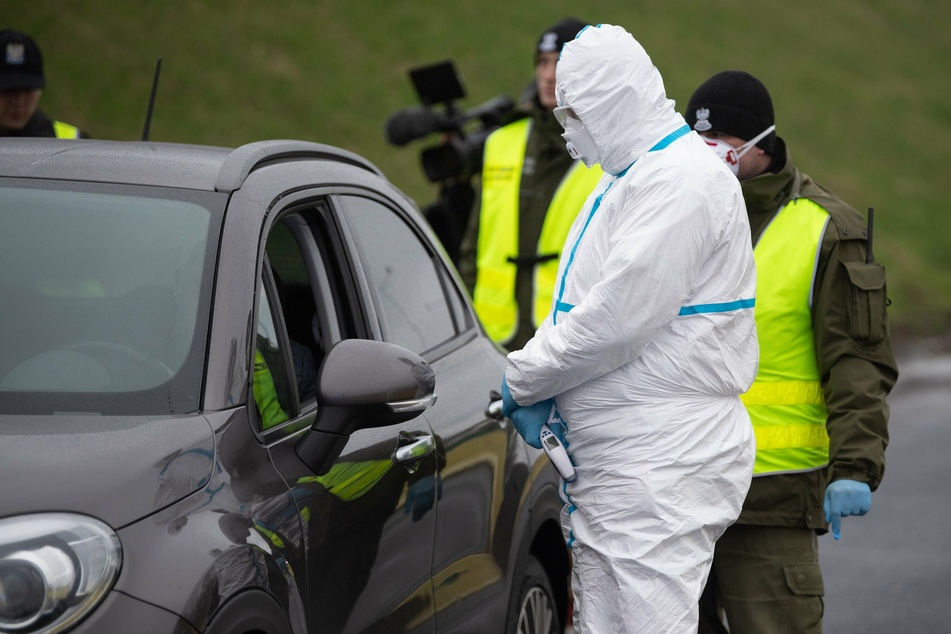 Ein Mitarbeiter des polnischen Rettungsdienstes kontrolliert in Schutzkleidung auf der Autobahn 4 an der polnisch-deutschen Grenze einen Autofahrer.