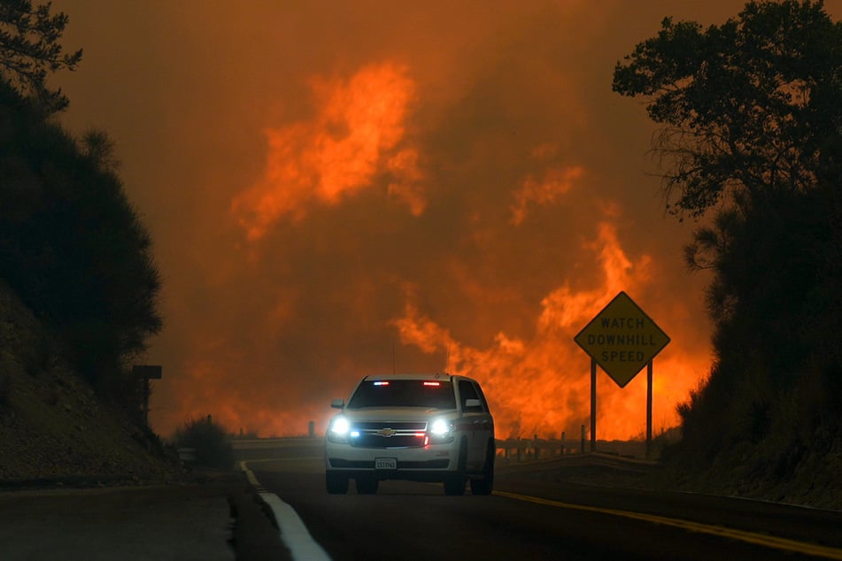 Das Line Fire überspringt den Highway 330, als ein Autofahrer vorbeifährt.