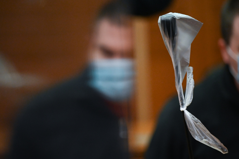 Der Angeklagte spiegelt sich zu Beginn des Mordprozesses im Gerichtssaal des Landgerichts Frankfurt in einer Trennscheibe.