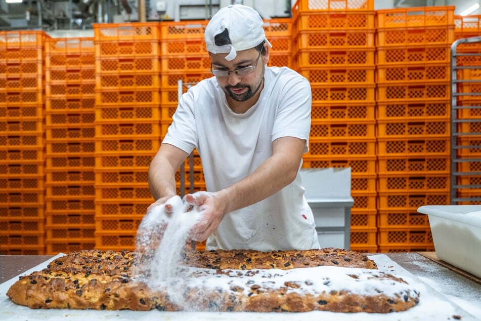 Mitarbeiter Tom Strauch (29) bestreut die fertig gebackenen Stollen mit Zucker.