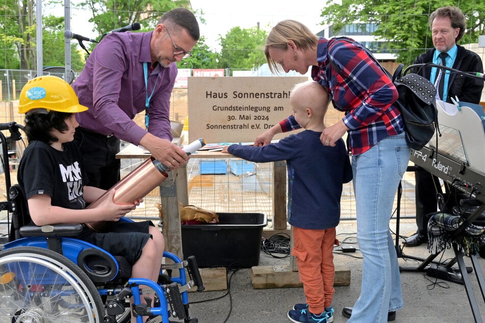 Die zwei jungen Patienten Adam (12, l.) und Fabian (5) helfen beim Befüllen der Grundstein-Kapsel.