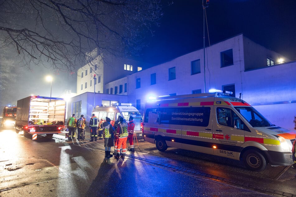 Einsatzkräfte stehen vor dem Krankenhaus in Neustadt bei Coburg, wo Sonntagfrüh ein Feuer ausgebnrochen ist.