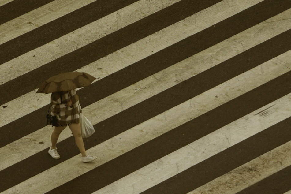 Mit einem Regenschirm schützt sich eine Frau in Spanien vor dem herabfallenden Staubregen.
