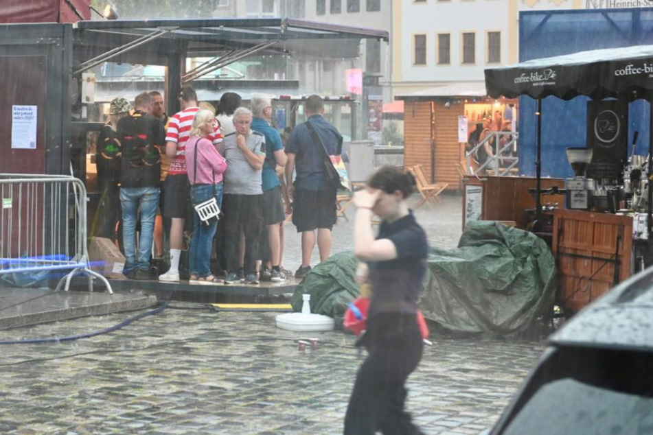 Stadtfestbesucher suchen unter jedem Vordach Schutz vor dem heftigen Regen.