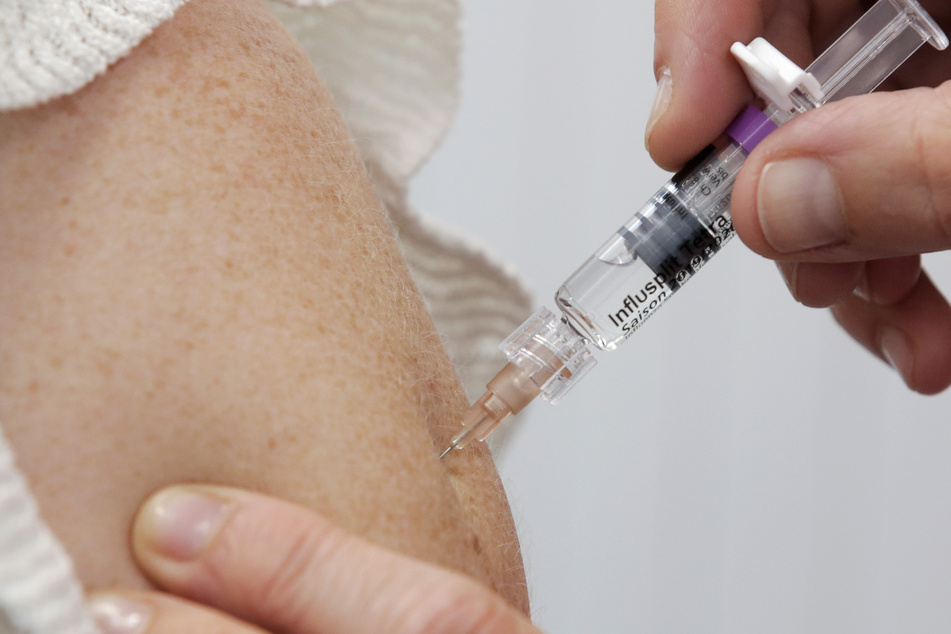 Ein Ärztin impft eine Patientin mit einer intramuskulären Injektion gegen Grippe.