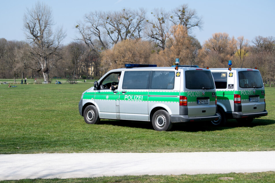Zwei Polizeifahrzeuge stehen im Englischen Garten. (Archiv)