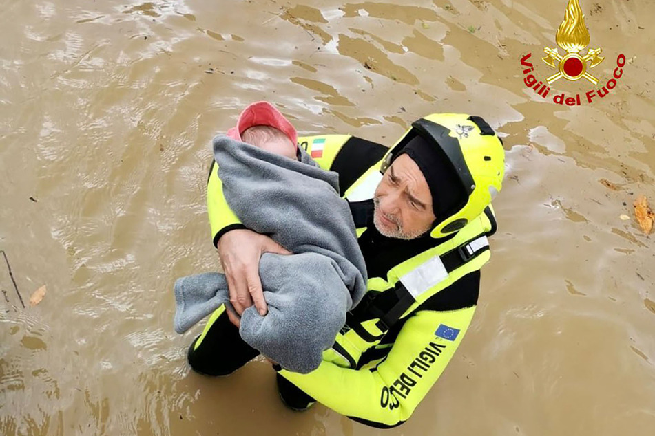 Ein Feuerwehrmann evakuiert aus dem überfluteten Haus der Familie ein wenige Monate altes Mädchen.