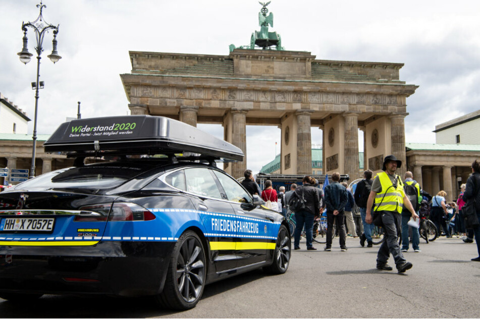 Ein Tesla mit den Aufschriften "Friedensfahrzeug" und "Widerstand 2020" steht bei einer Demonstration gegen die Stationierung von US-Atomwaffen in Ramstein am Brandenburger Tor.