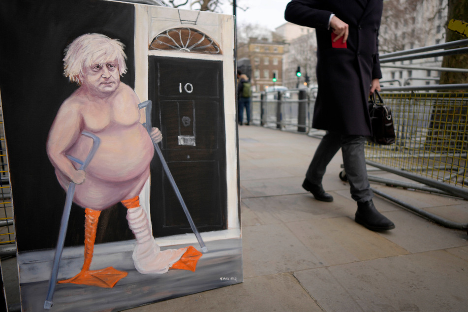 Ein Mann geht vor der Downing Street an einer Karikatur vorbei, die den britischen Premierminister als lahme Ente zeigt.