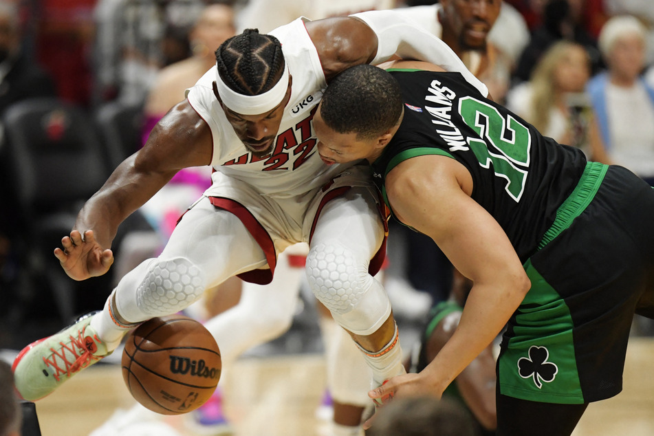 Jimmy Butler (l.) tussles for the ball with Celtics forward Grant Williams.