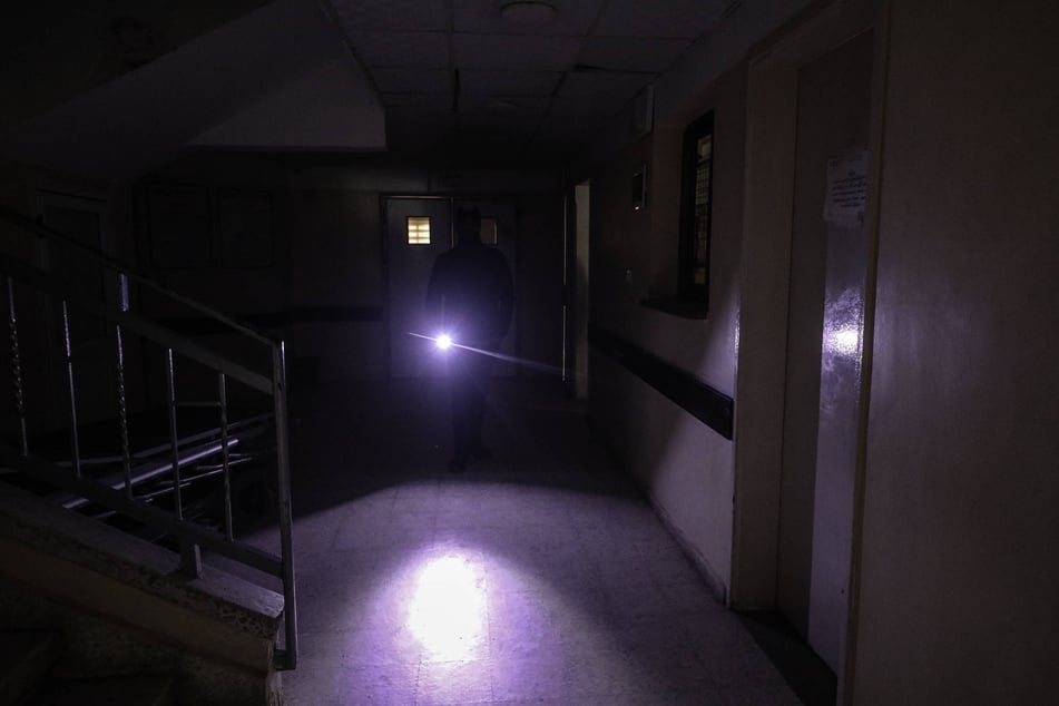 A person holds a flashlight in the dark at Al-Awda Hospital, which has announced that it has suspended medical services due to running out of fuel, in the Nuseirat Refugee Camp, Deir al-Balah, Gaza, on December 25, 2025.