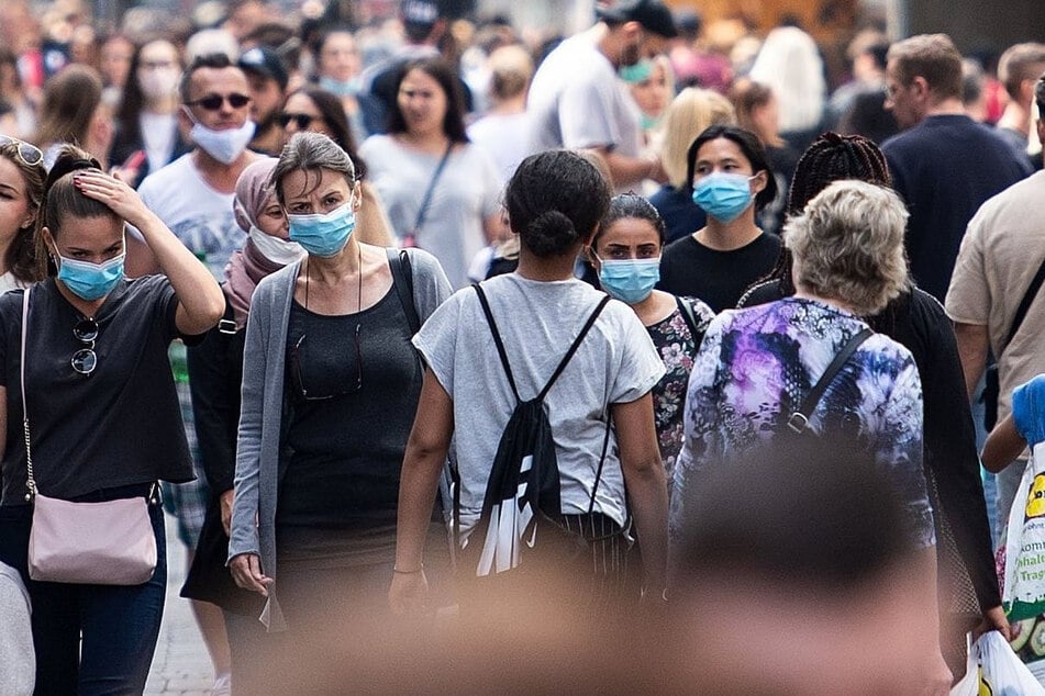 Zahlreiche Menschen mit Masken sind auf der Schildergasse, einer der Haupteinkaufsstraßen Kölns, unterwegs.