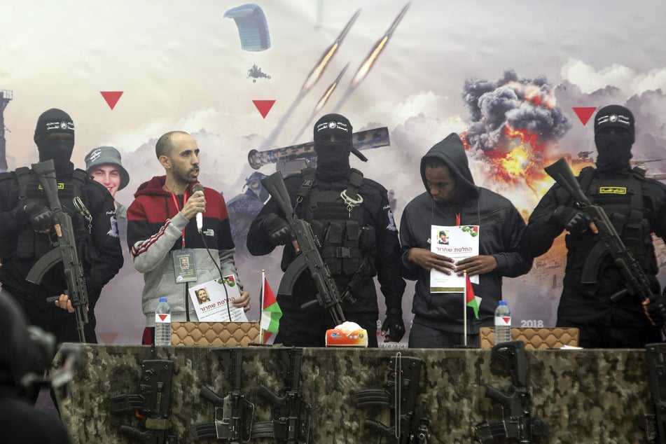 Die israelischen Geiseln, Tal Shoham (l.) und Avera Mengistu, stehen zwischen vermummten und bewaffneten Mitgliedern der Terrororganisation Hamas.