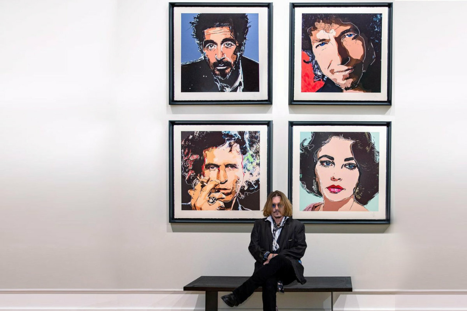 Johnny Depp poses with his portraits of Al Pacino, Bob Dylan, Keith Richards, and Elizabeth Taylor.
