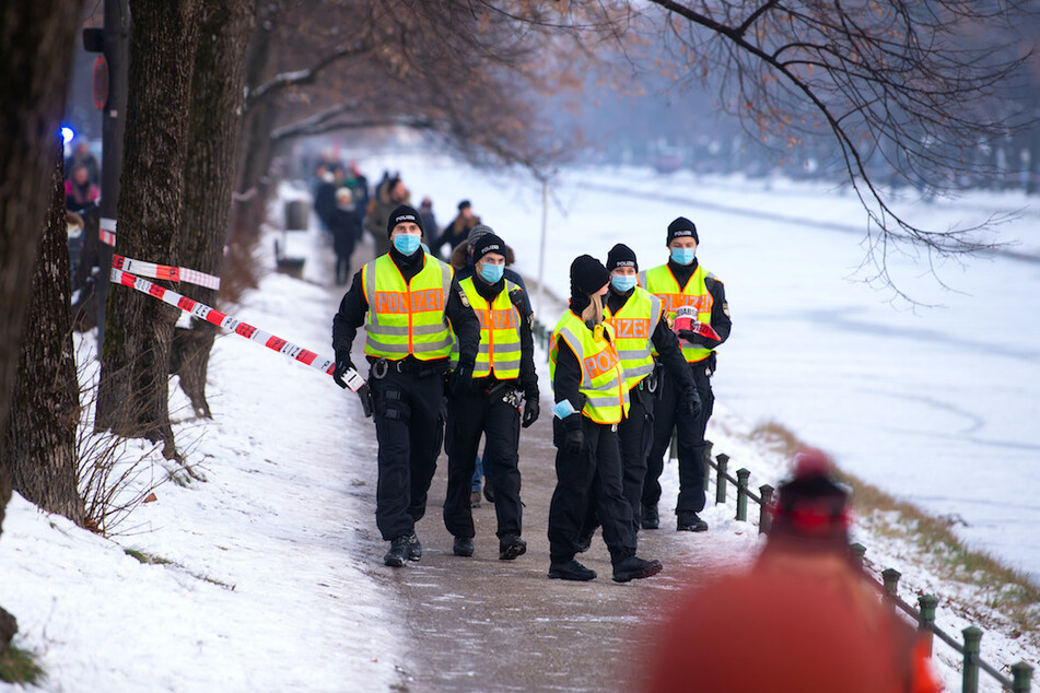 Polizisten räumen und sperren die Eisfläche und die Gehwege am Nymphenburger Kanal in München.