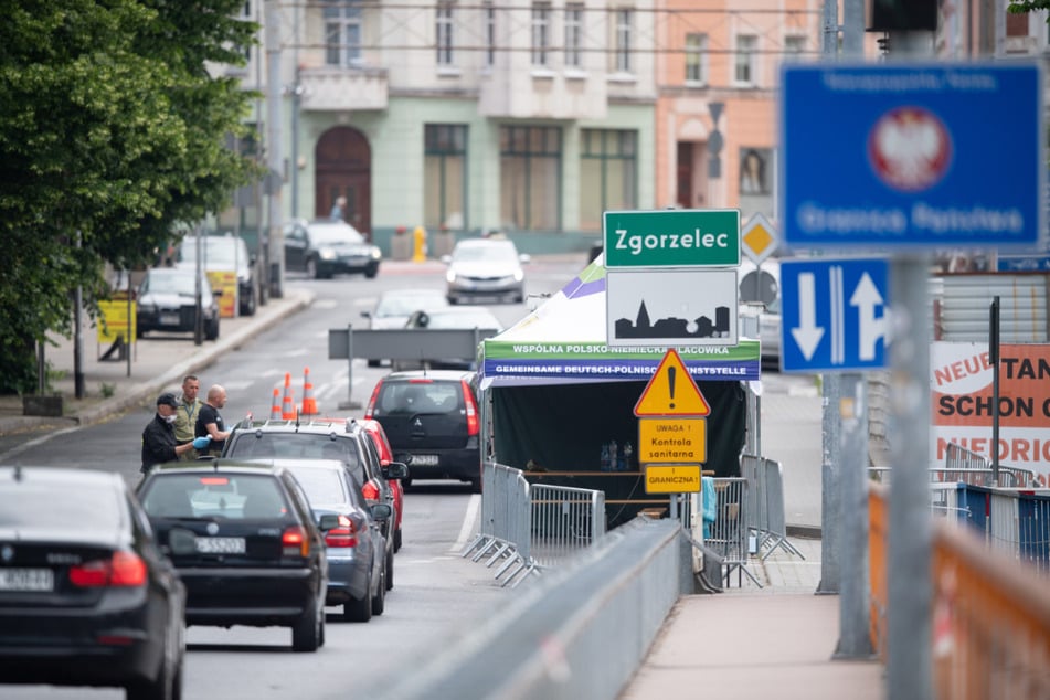 Polnische Grenzpolizisten stehen auf der Brücke der Freundschaft an der polnischen Grenze vor Zgorzelec und kontrollieren mit einem Thermometer die Körpertemperatur der Autofahrer, die aus Görlitz kommend nach Polen einreisen wollen.