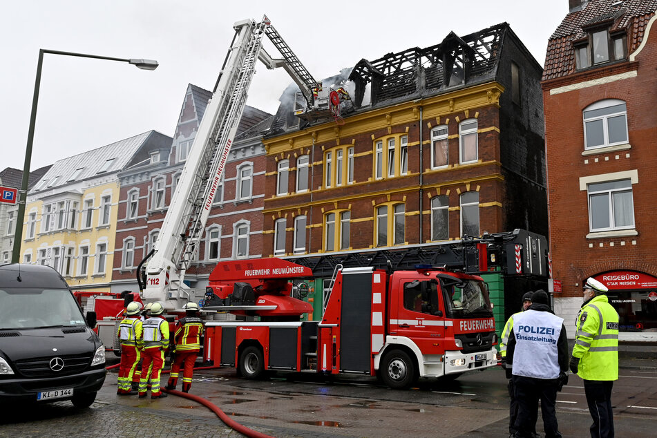 Feuerwehrleute bekämpfen Glutnester nach dem Brand in dem Mehrfamilienhaus.